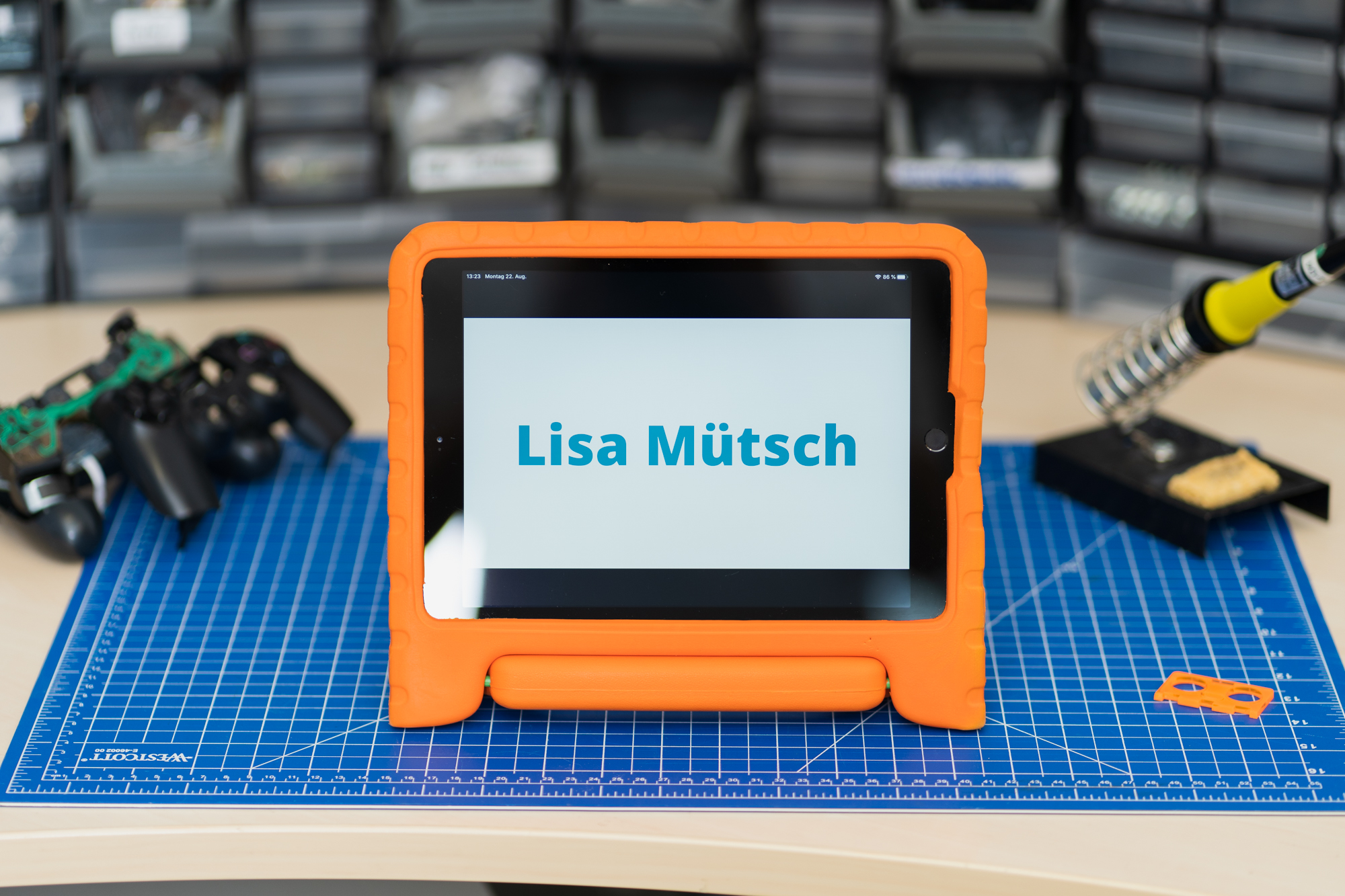 Zu sehen ist ein iPad auf einem Schreibtisch. Das iPad zeigt den Namen Lisa Mütsch.
