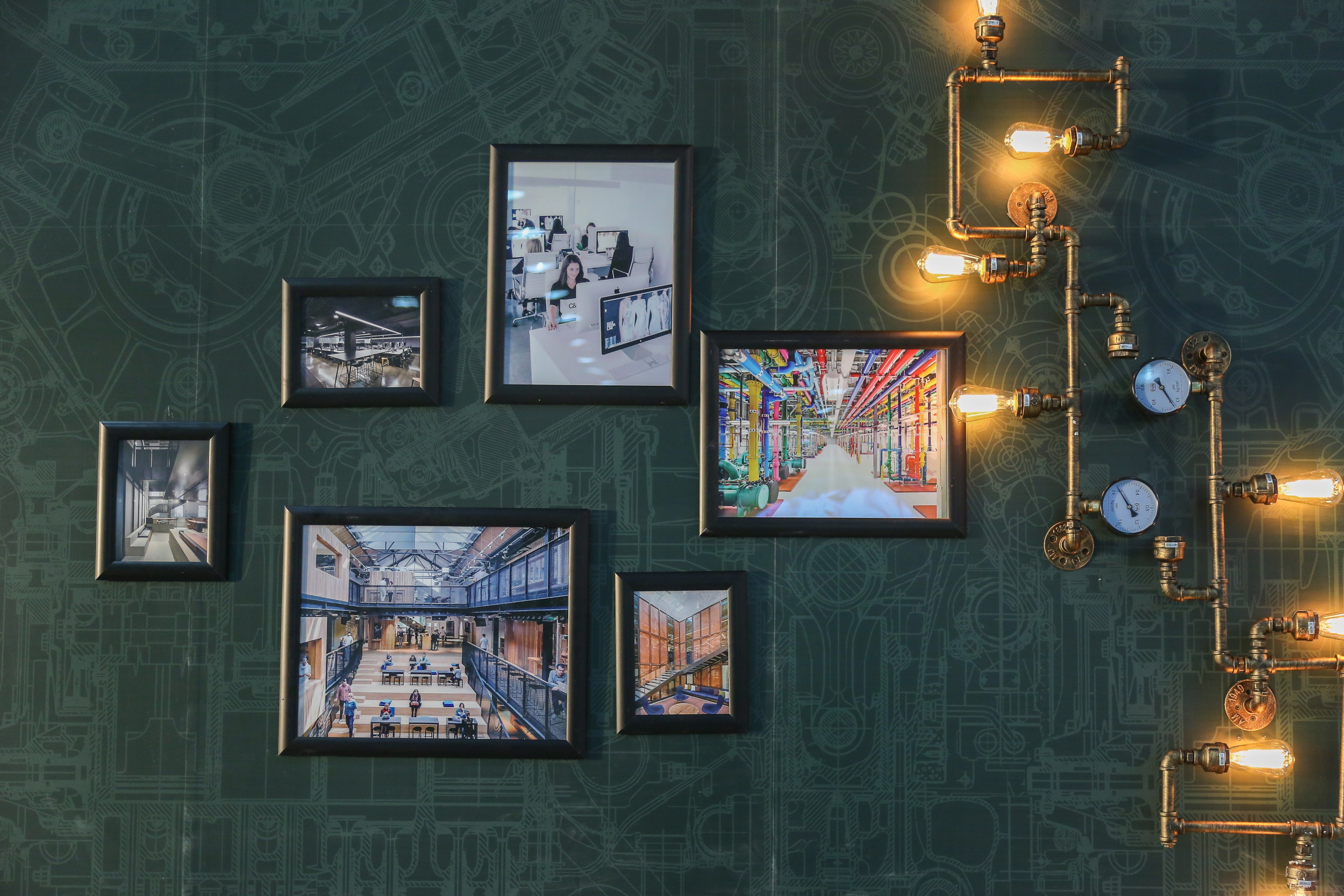 Auf einer Wand hängen Bilder, Tablets und eine industrielle Lampe, die für die Lösung des Escape Rooms gebracht werden.