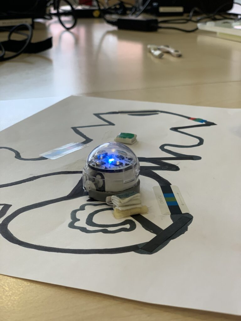 Kleiner Roboter (Ozobot) auf Blatt Papier mit einem gezeichneten Labyrinth.
